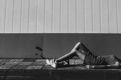 Side view of woman lying on wall