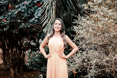 Portrait of smiling young woman standing against plants