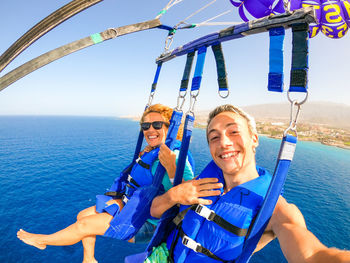 Portrait of smiling mother and son parasailing at sea