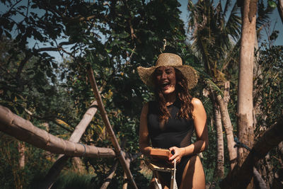 Young woman sitting on tree trunk in forest