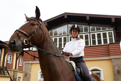 Side view of man riding horse against sky