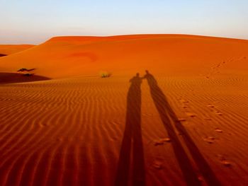 Shadow of person on sand dune in desert against clear sky