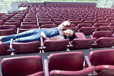 High angle view of girl lying down on seats in stadium