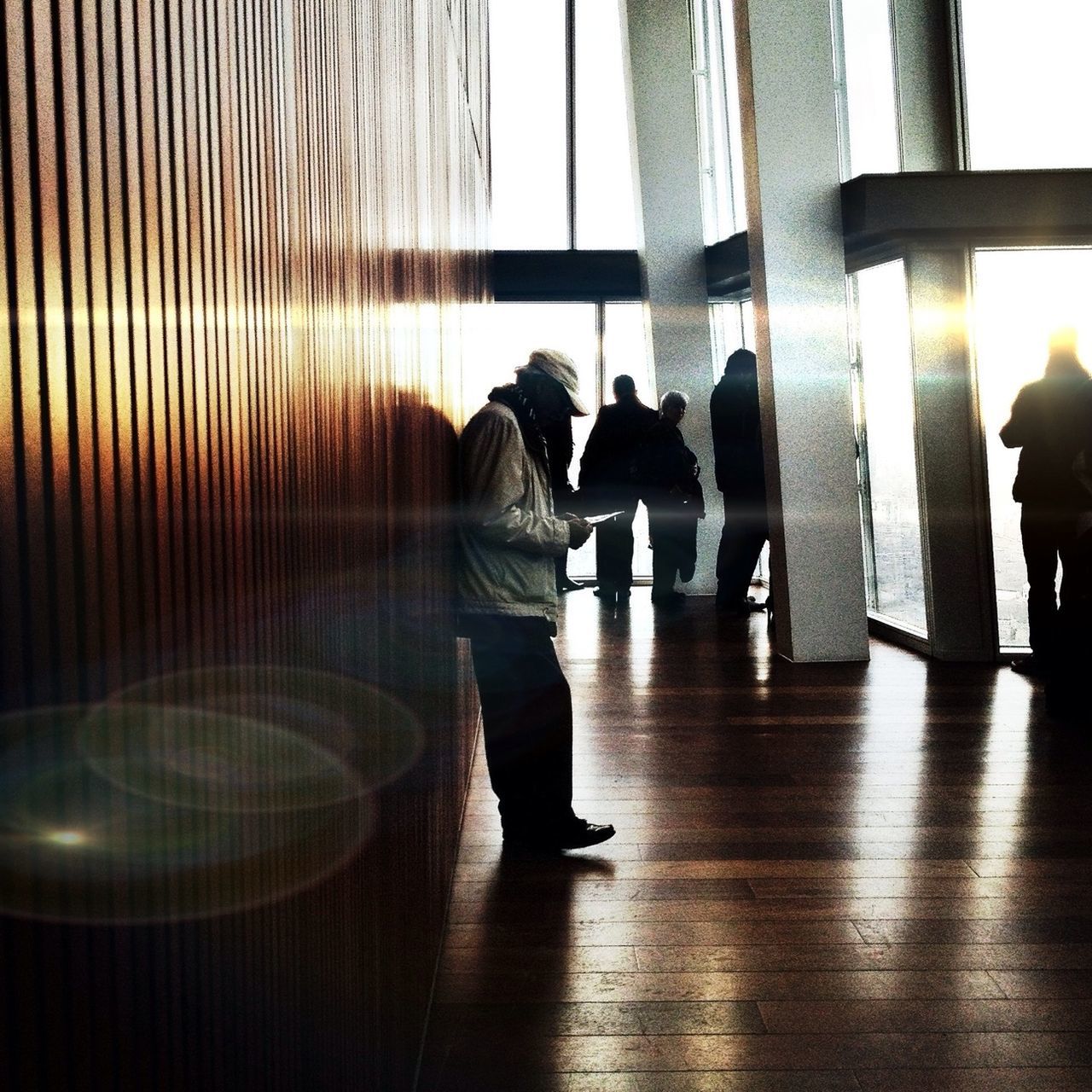 indoors, lifestyles, architecture, built structure, men, rear view, leisure activity, full length, person, window, standing, walking, sunlight, silhouette, glass - material, reflection, railing