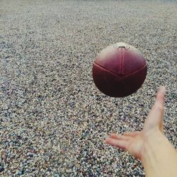 Cropped image of person playing america football on beach