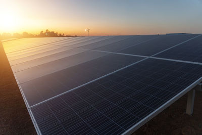 Solar panels on beach against sky during sunset