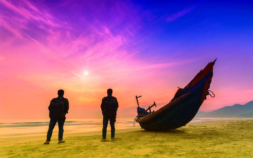 Silhouette people on beach against sky during sunset