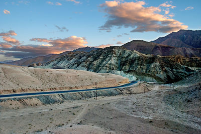 Road by mountains against sky during sunset