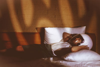 Girl wearing helmet while lying on bed at home