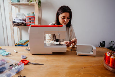 Young woman using phone while sitting on table at home