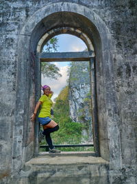 Side view of man standing by window