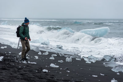 Man standing at beach during winter