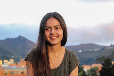 Portrait of smiling young woman against mountains