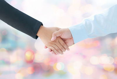 Close-up of couple holding hands against sky