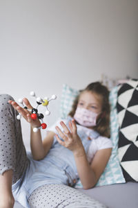 Girl playing with toy lying on bed at home