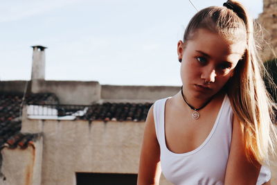 Portrait of young woman standing against built structure