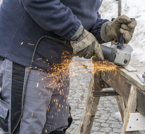 Midsection of man grinding metal at workshop