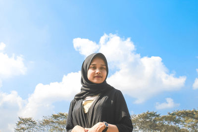 Portrait of smiling woman standing against sky