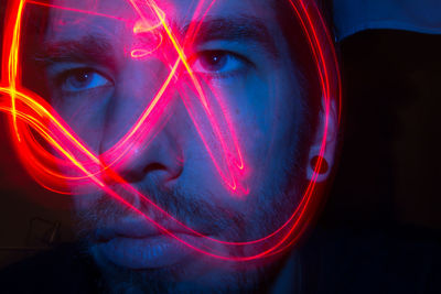 Close-up portrait of illuminated man against black background