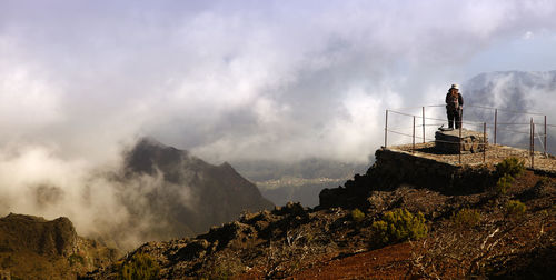 Panoramic view of man standing on mountain against sky