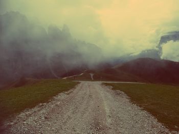 Dirt road along landscape against sky