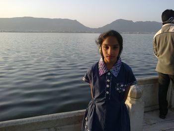 Portrait of woman standing by lake against mountains