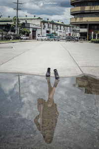 Man photographing in city against sky