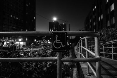 Wheelchair sign on railing in city at night