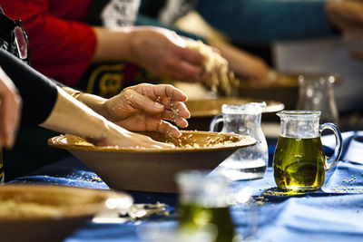 Close-up side view of hands kneading dough