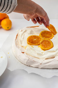 Close-up of hand decorating ice cream with orange slices on table