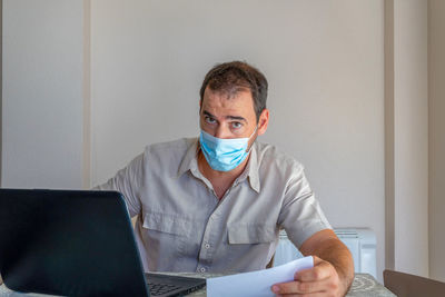 Frustrated man wearing flu mask sitting at office