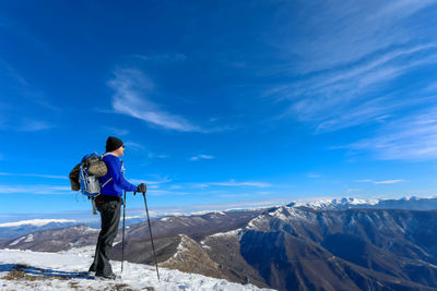 Rear view of man standing on mountain against sky