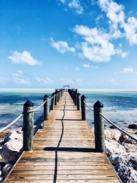 Wooden pier on sea against sky