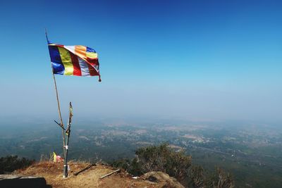 Multi colored flag on landscape against blue sky