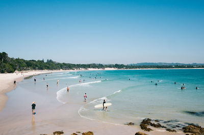 People on beach against clear blue sky