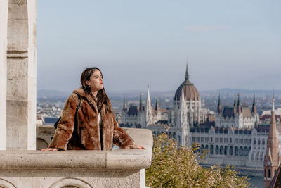 Portrait of girl standing on balcony overlooking city of budapest, hungary