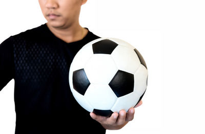 Midsection of man holding soccer ball against white background