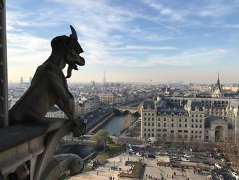 Close-up of gargoyle statue against cityscape