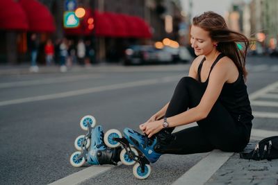 Full length of woman sitting on street in city