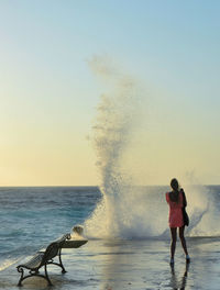 Rear view of woman on beach against clear sky