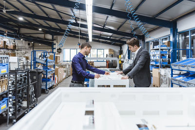 Business people standing on shop floor, discussing product improvement