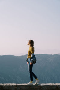 Rear view of woman standing against sky during sunset