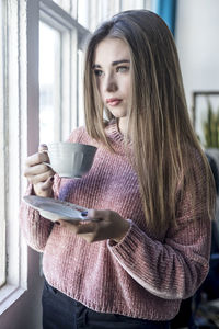 Portrait of smiling young woman drinking glass