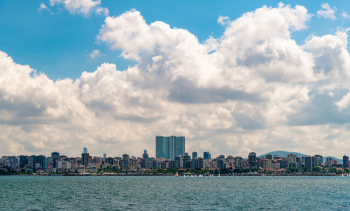 Sea by buildings against sky in city