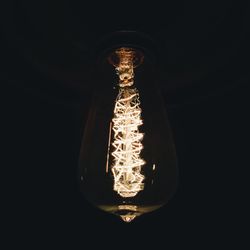 Low angle view of illuminated light bulb in darkroom