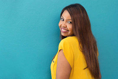 Portrait of young woman against blue background