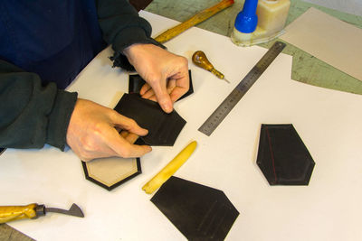 Midsection of man making wallet on table