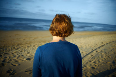 Rear view of man on beach against sky