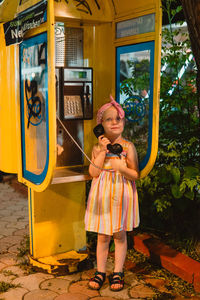 Little girl talking on a phone booth