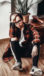 Portrait of young man sitting on hardwood floor